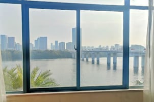 A view from a window overlooking a river with a bridge and a city skyline in the background.