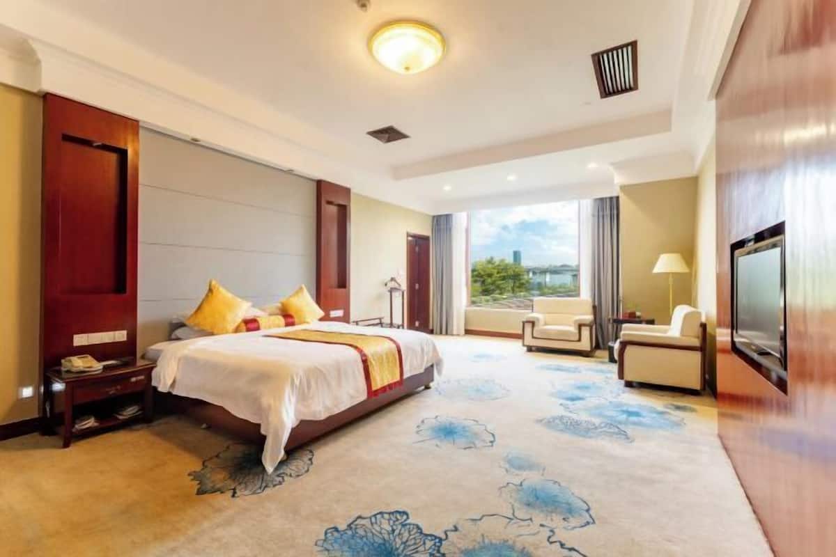 Une chambre d’hôtel avec un grand lit, un canapé, une télévision et une vue sur l’extérieur.