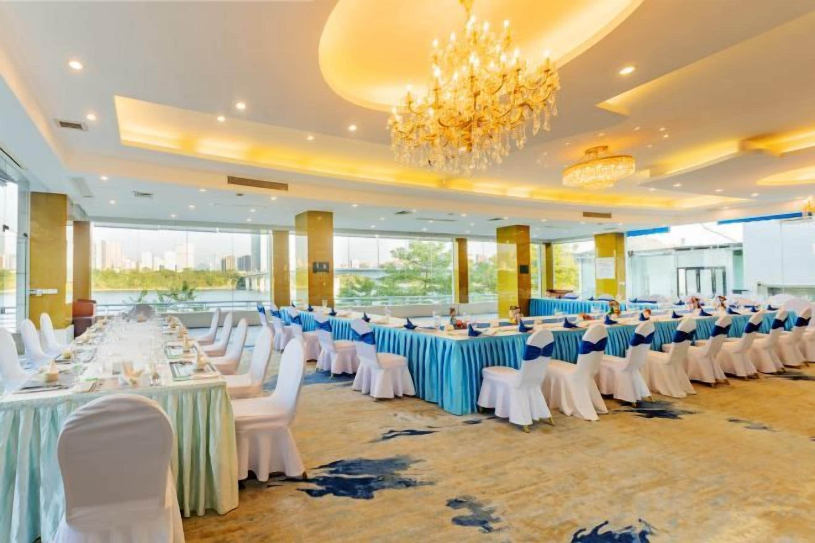 A banquet hall with round tables, chairs, and a chandelier.
