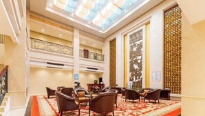 A hotel lobby with a grand staircase, a red patterned carpet, and a high ceiling with a skylight. - Liuzhou Hotel (Liuzhou)