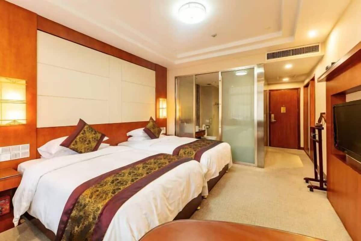 Une chambre d’hôtel avec deux lits, une télévision, un bureau et une porte coulissante donnant accès à la salle de bain.