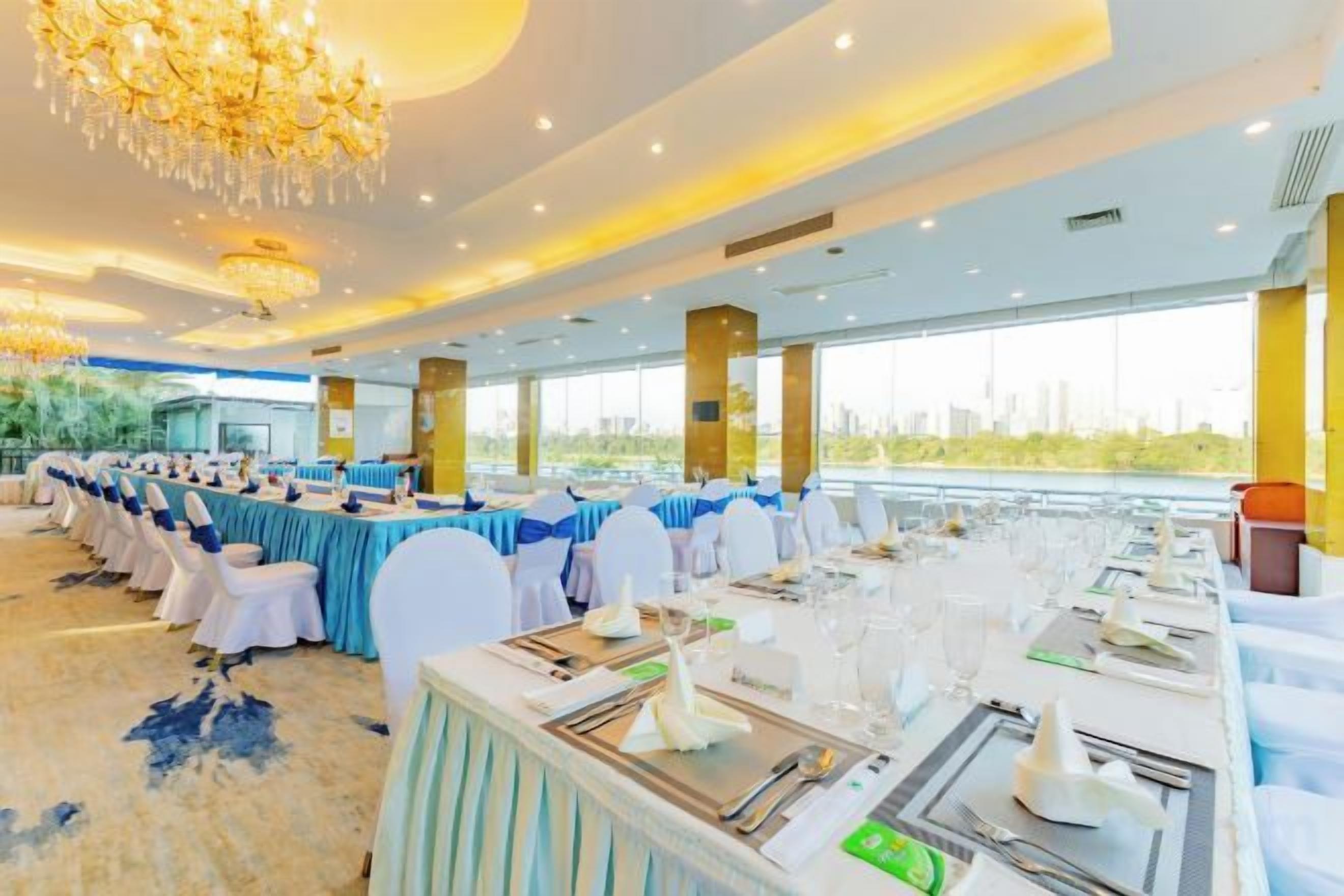 A banquet hall with round tables, white chairs, and a chandelier.