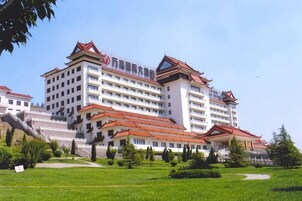 Un hotel de varios pisos con un estilo arquitectónico tradicional, que presenta un tejado rojo y paredes blancas.