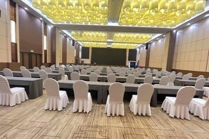 A conference room with rows of tables and chairs, a large screen, and a patterned ceiling. - Wanjie International Hotel (Zibo)