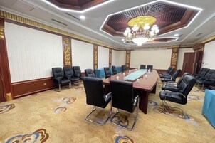 Un salón de conferencias con una larga mesa, varias sillas y una araña de cristal.
