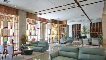A spacious lobby with seating areas, a coffee table, and a bookshelf.