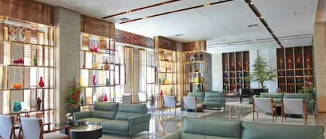Eine geräumige Lobby mit Sitzbereichen, einem Couchtisch und einem Bücherregal.