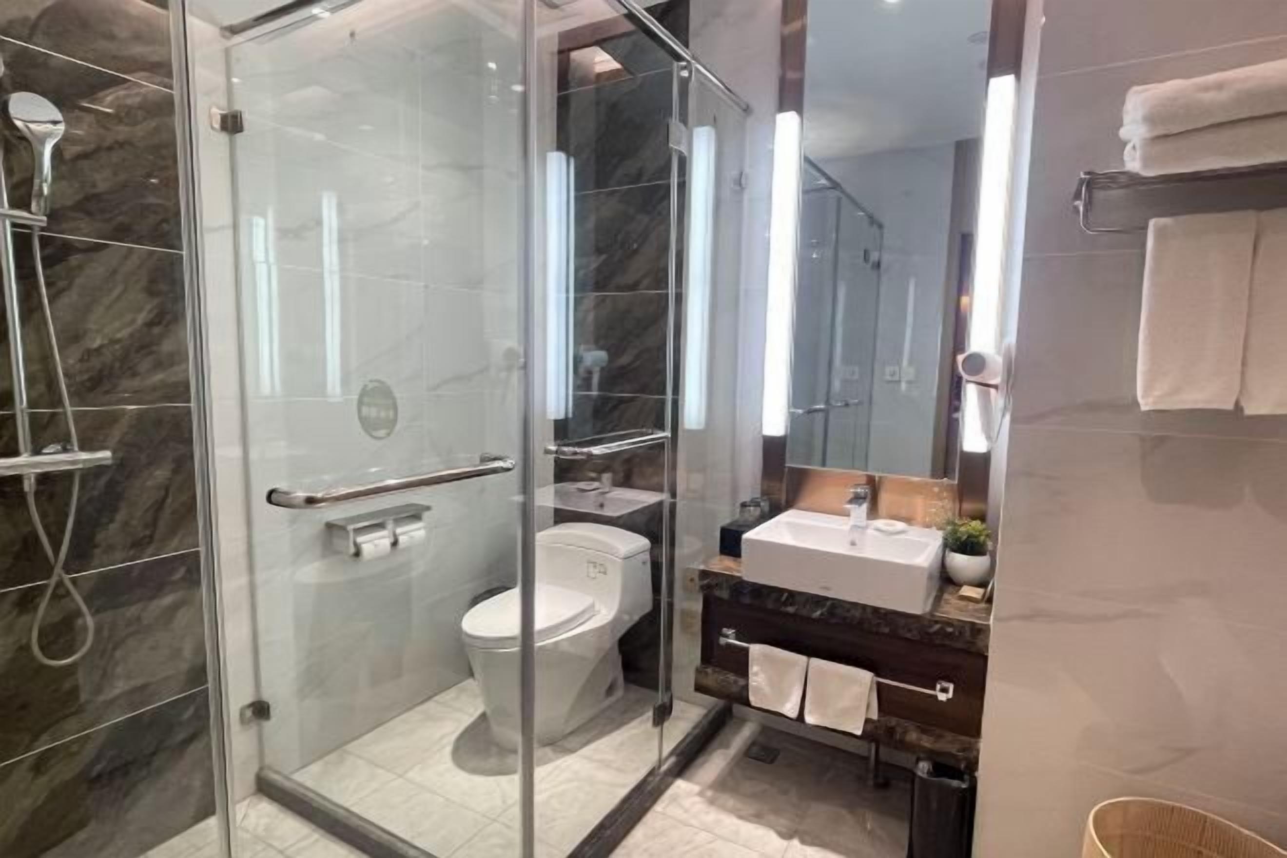 Een moderne badkamer met een douchecabine van glas, een toilet en een wastafel met spiegel.
