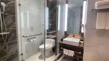Een moderne badkamer met een douchecabine van glas, een toilet en een wastafel met spiegel.
