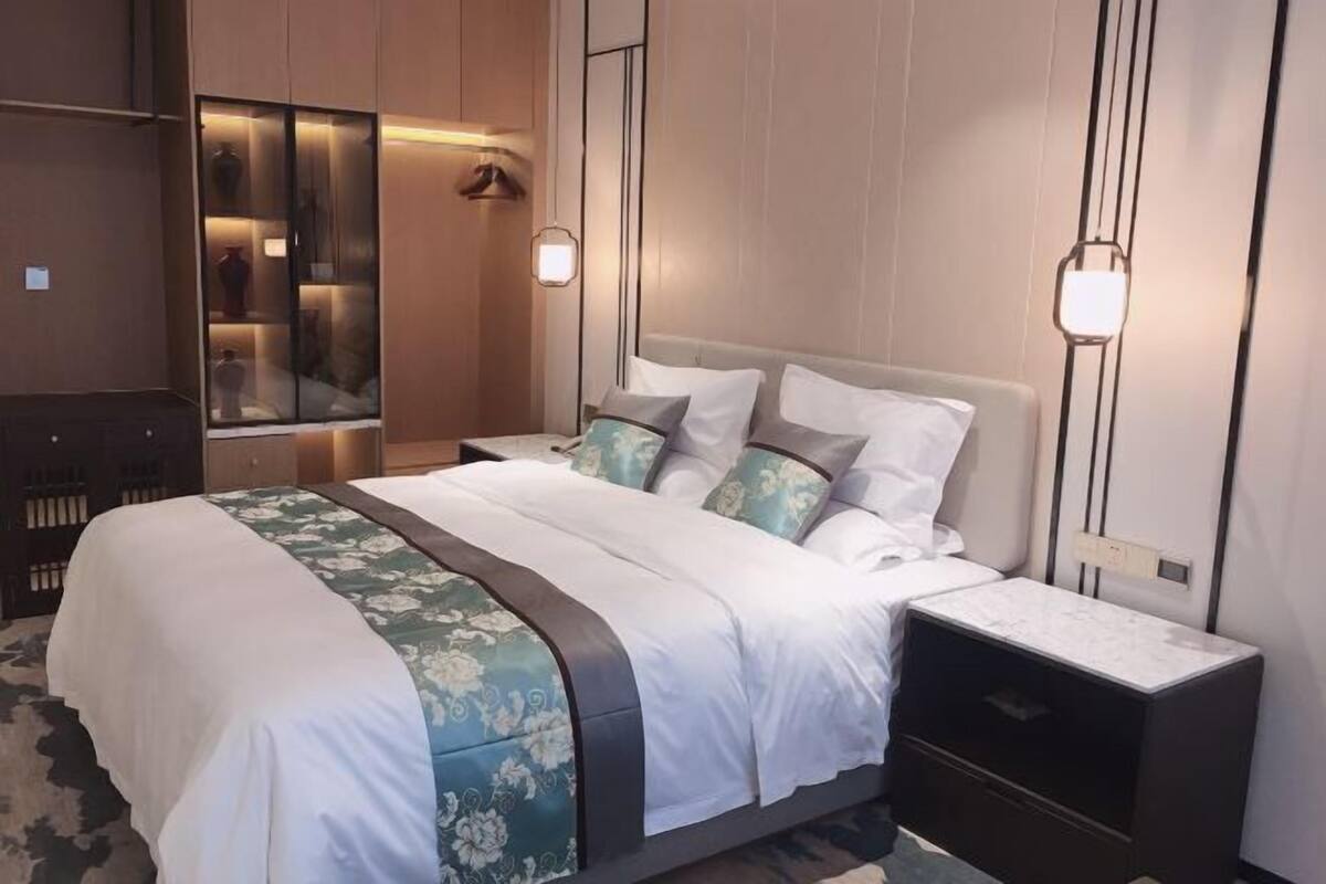 A bedroom with a bed, bedside tables, a wardrobe, and a mirror.