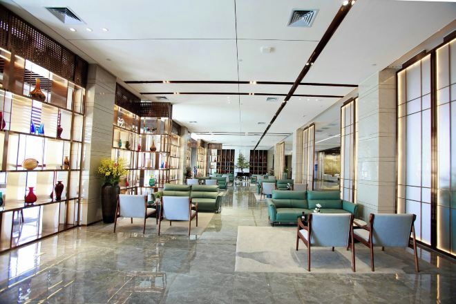A hotel lobby with a long corridor, seating areas, and a bookshelf.