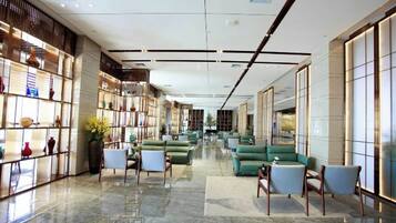 A hotel lobby with a long corridor, seating areas, and a bookshelf.