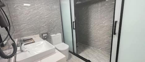 A modern bathroom with a white sink, toilet, and glass shower enclosure.