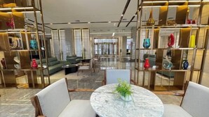 Eine moderne Lobby mit einem runden Marmortisch, Sitzgelegenheiten und dekorativen Regalen.