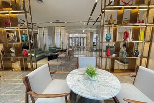 Um lobby moderno com uma mesa de mármore, assentos e vasos decorativos.