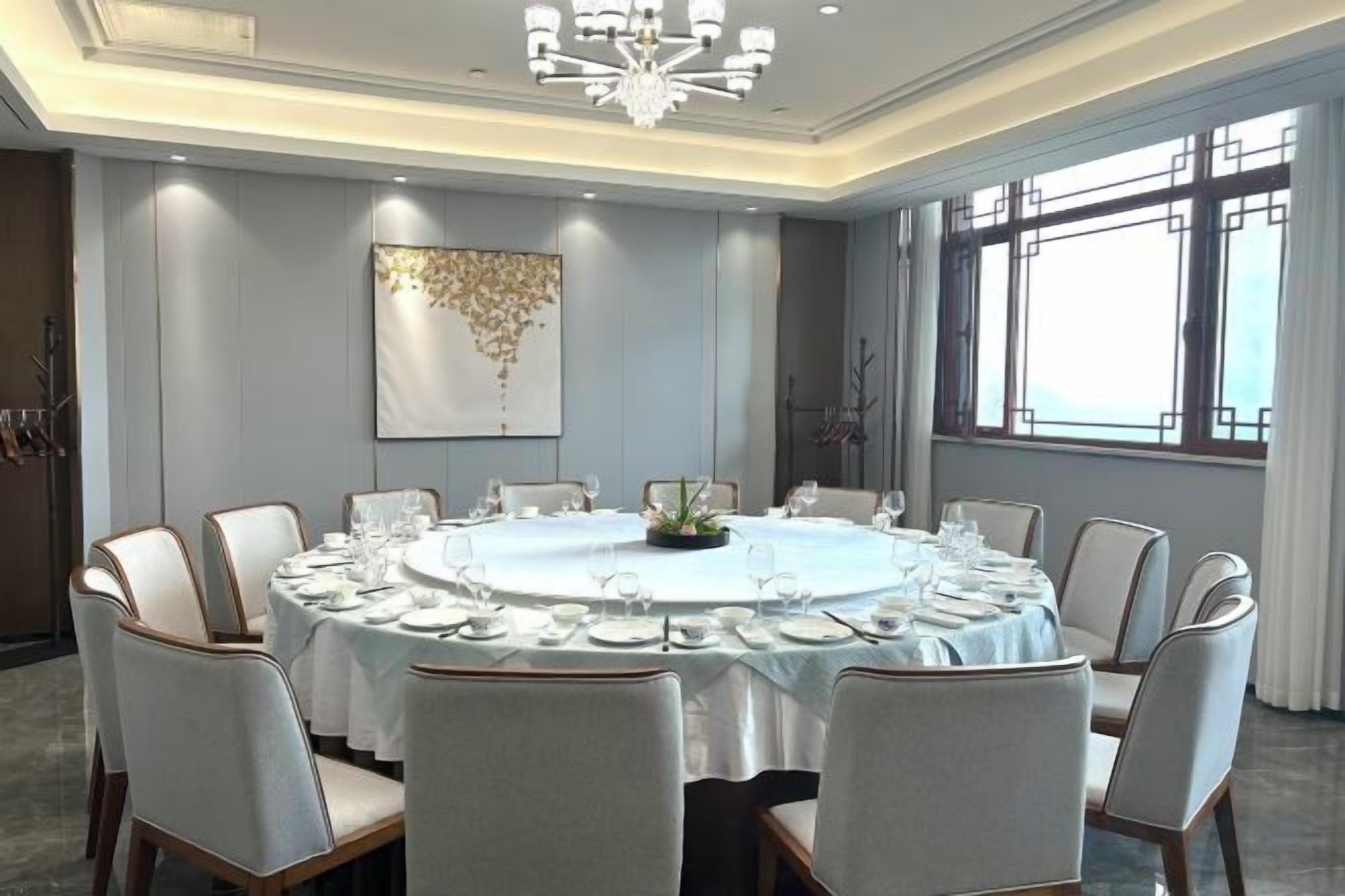 A conference room with a round table, chairs, and a chandelier.