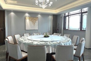 A conference room with a round table, chairs, and a chandelier. - Wanjie International Hotel (Zibo)