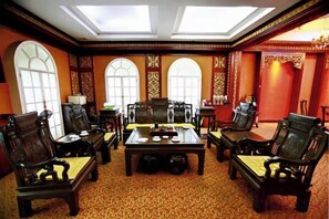 A traditional meeting room with a high ceiling, ornate walls, and a central table surrounded by chairs. - Wanjie International Hotel (Zibo)