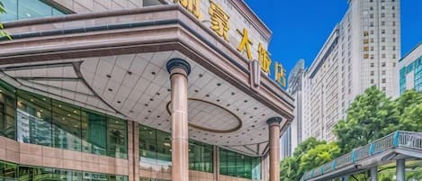 A modern building with a prominent entrance, large columns, and a clear sky.