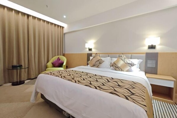 A hotel room with a bed, bedside tables, a chair, curtains, and wall-mounted lights. - Regal Hotel (Guiyang)