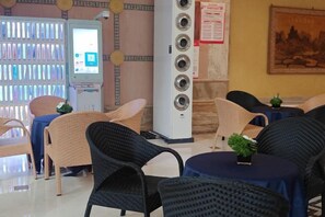 A hotel lobby with wicker chairs, a vending machine, and a large speaker system. - Regal Hotel (Guiyang)