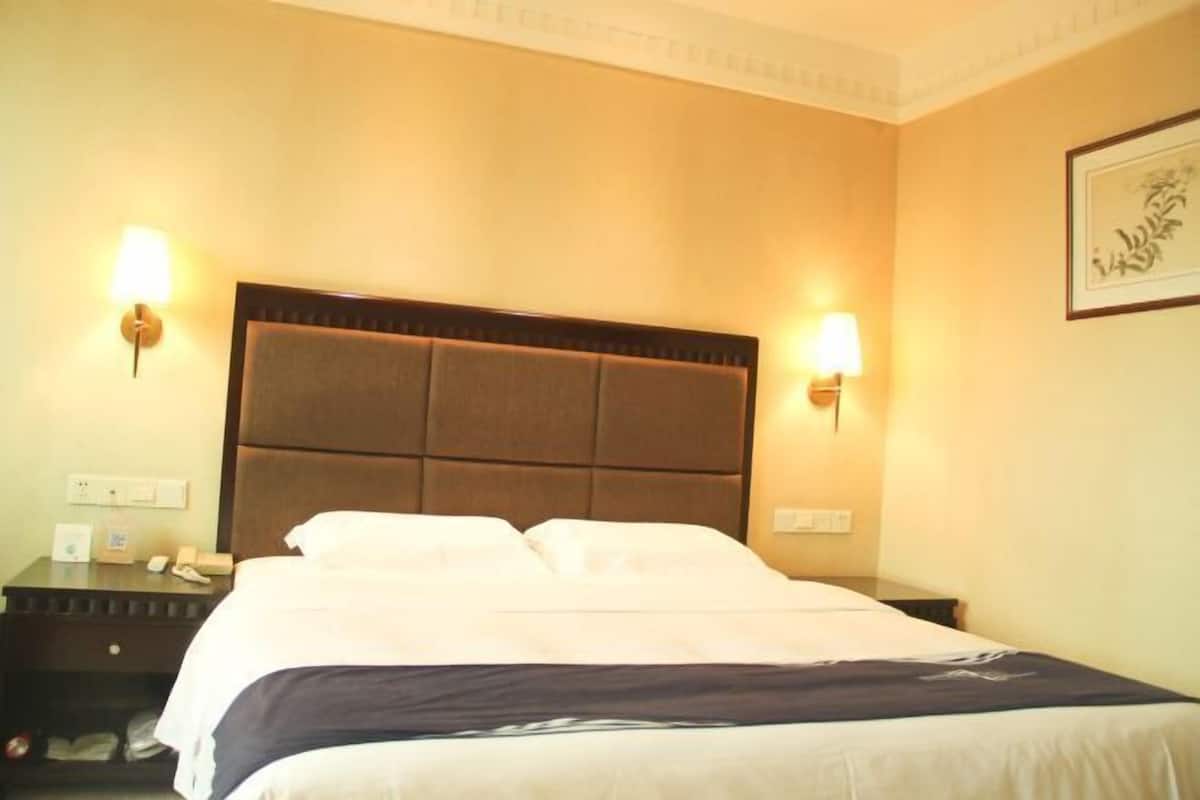 Habitación de hotel con una cama grande, dos mesitas de noche y lámparas fijadas a la pared.