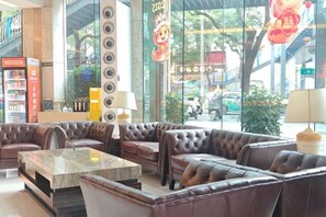 A lobby with leather sofas, a marble coffee table, and a reception desk. - Regal Hotel (Guiyang)