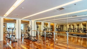 A gym with exercise equipment, wooden flooring, and mirrored walls. - Regal Hotel (Guiyang)