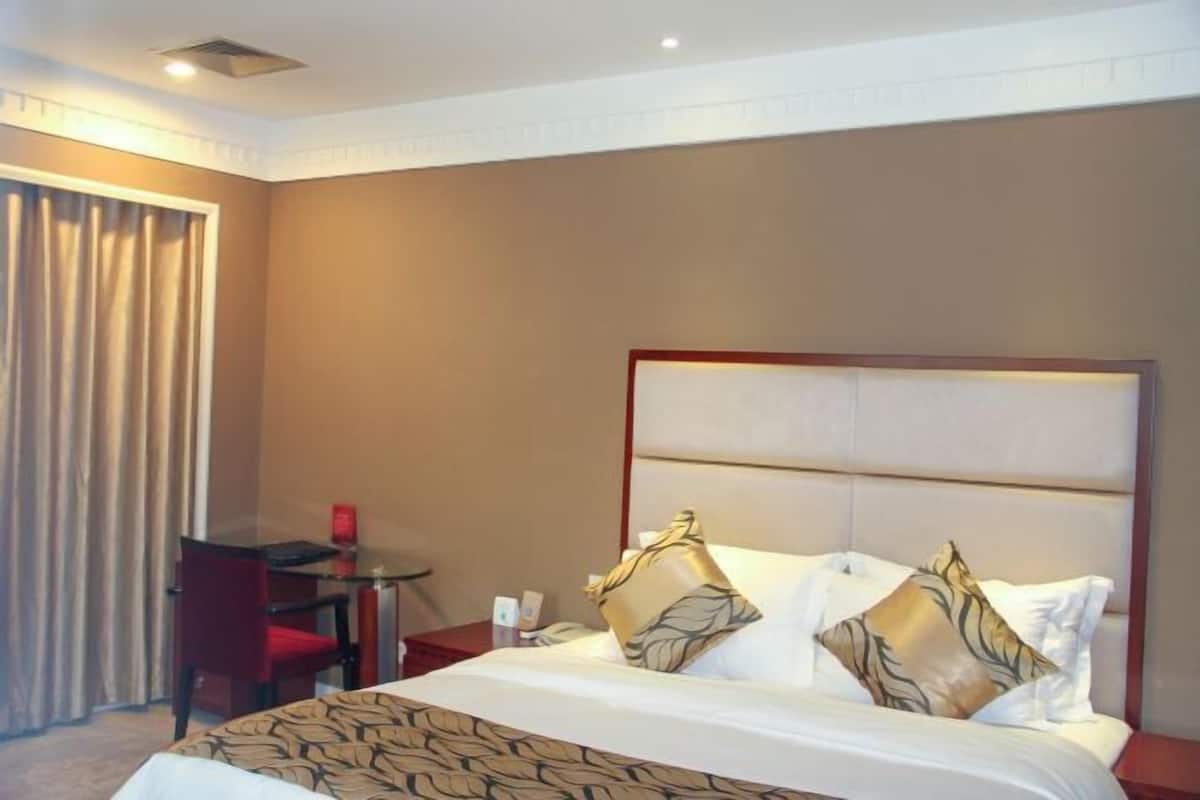 Una habitación de hotel con una cama grande, un escritorio y una silla.