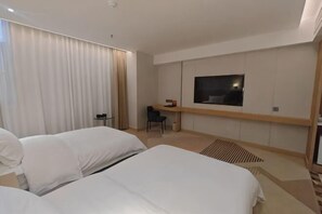A hotel room with two beds, a desk, a chair, a TV, and a large window with curtains. - Regal Hotel (Guiyang)