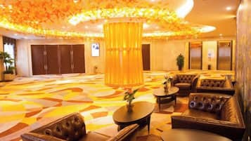 A hotel lobby with a large central column, seating areas, and a patterned floor.