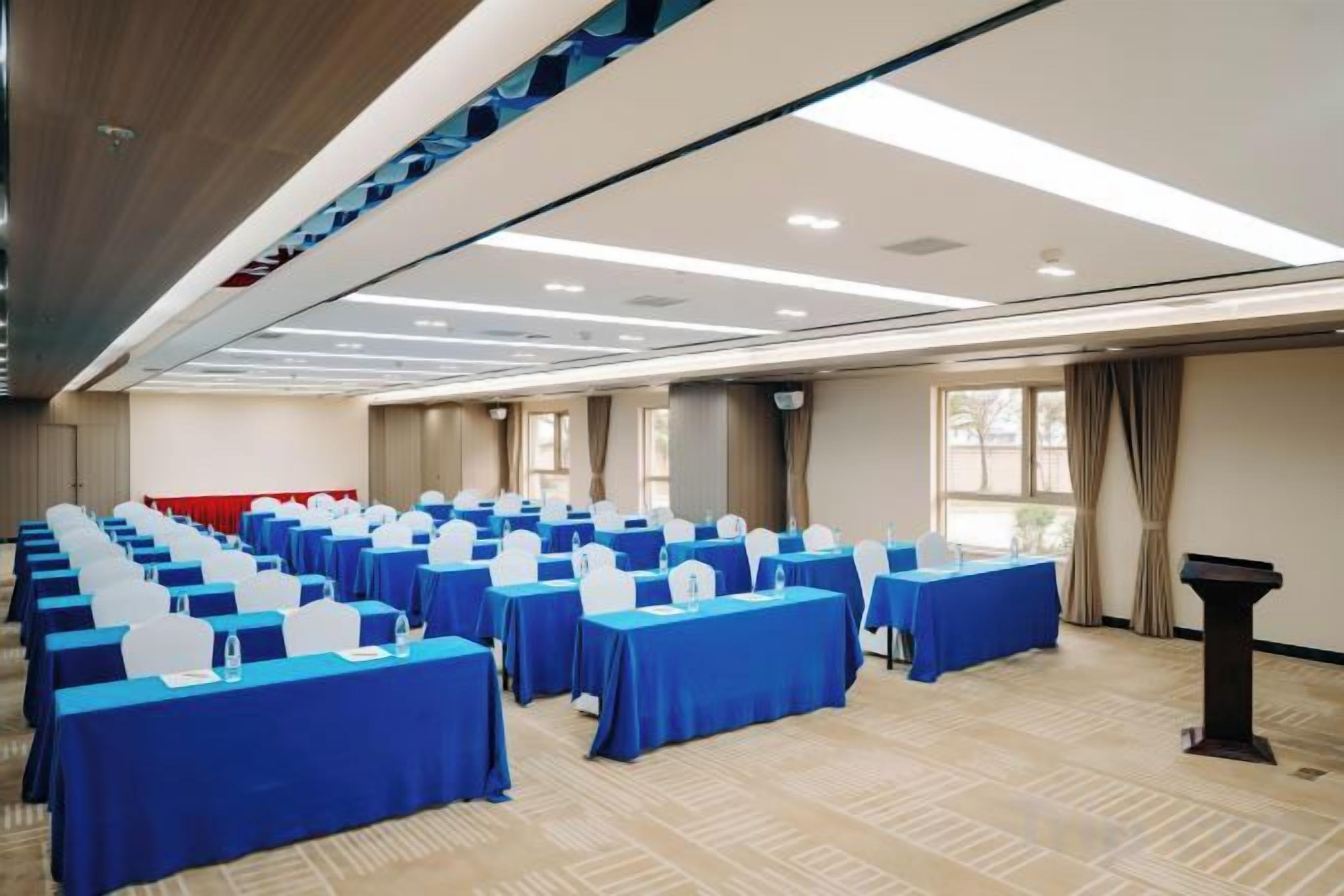 A conference room with rows of tables, a podium, and a carpeted floor.