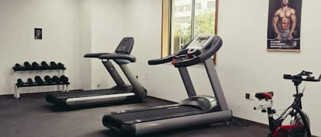 Ein Fitnessstudio mit Laufbändern, Kurzhanteln und einem Ergometer.
