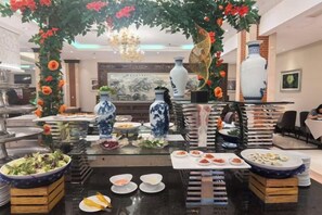Een buffetopstelling met diverse gerechten en decoratieve elementen zoals vazen en bloemen.