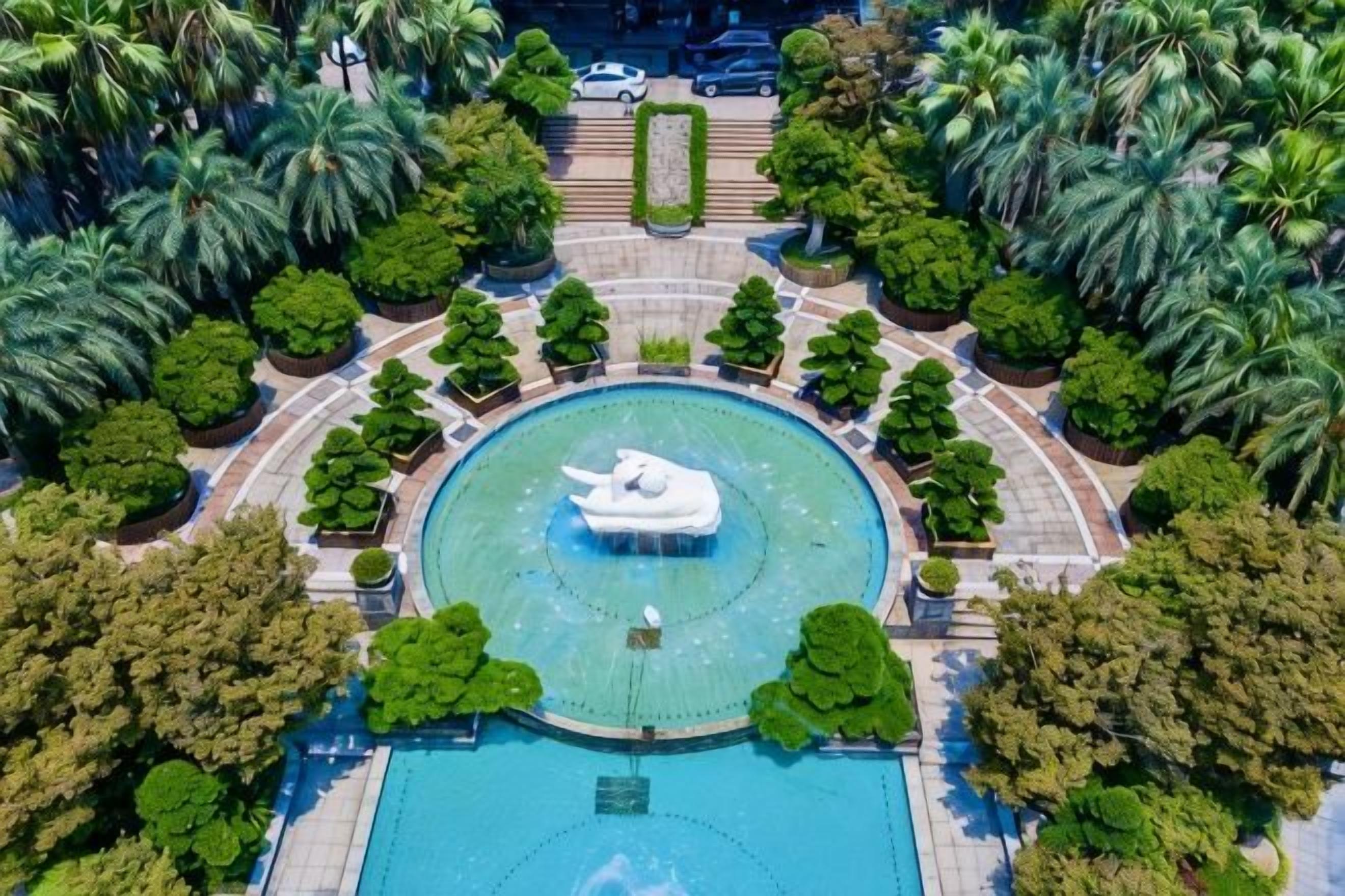 Une vue aérienne d’un parc circulaire avec une fontaine centrale, entouré d’arbres et de sentiers.