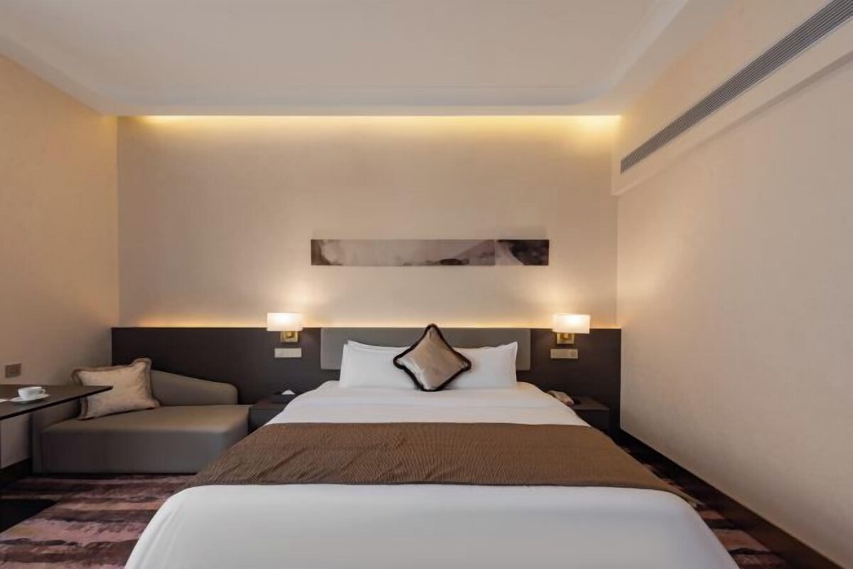 Een hotelkamer met een groot bed, nachtkastjes, een bureau en een stoel.