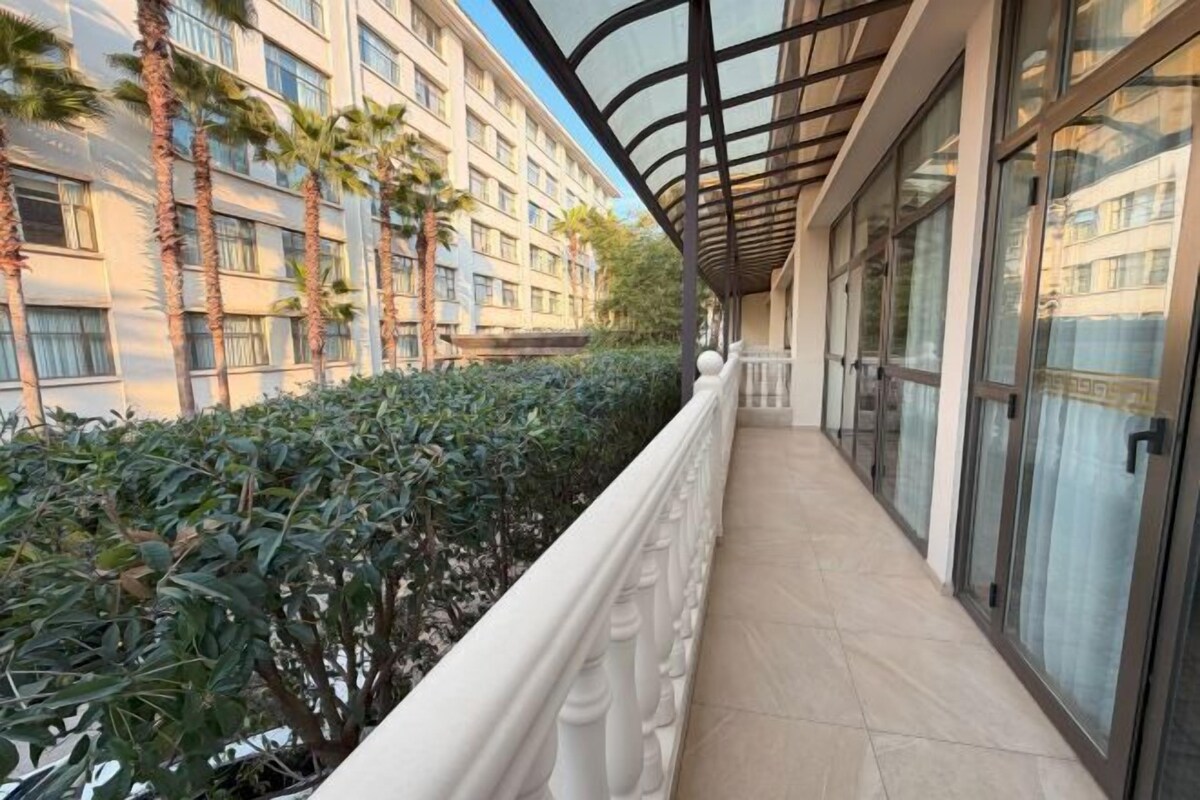 Een gang met glazen balustrade, een overdekte doorgang en een gebouw met meerdere verdiepingen en ramen.