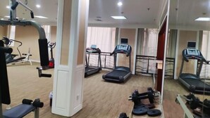 A gym with treadmills, a rowing machine, and free weights.