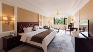 A hotel room with a large bed, bedside tables, a desk, and a view of the outdoors.