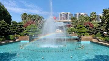 Una gran piscina al aire libre con una fuente central y un arcoíris.