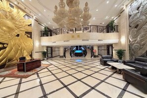 Een ruime lobby met een zwart-wit betegelde vloer, een receptiebalie en een zithoek met banken.