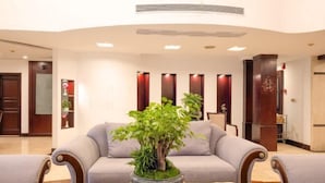 A lobby with a reception desk, seating area, and a plant centerpiece.