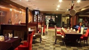 Un restaurant amb terra de pissos de graella, caires vermelles i beix, i taules preparades per dinar.