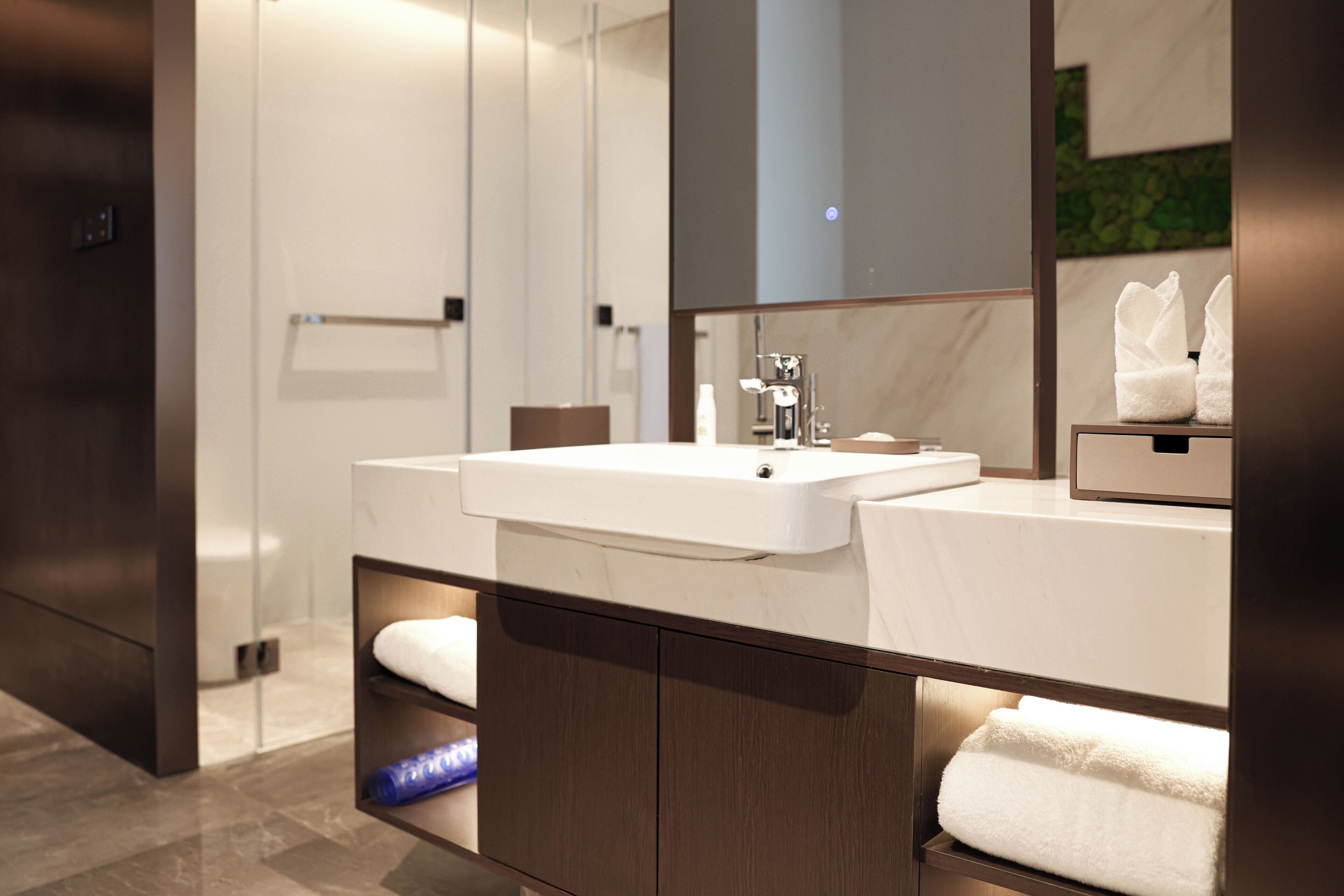 Un baño moderno con tocador doble lavamanos, un espejo grande y un perchero para toallas.