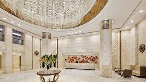 Eine geräumige Lobby mit Marmorboden, einer Rezeption und einer großen Kandelaber.