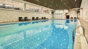 Ein großes Hallenbad mit Liegestühlen und einer Kachelwand.