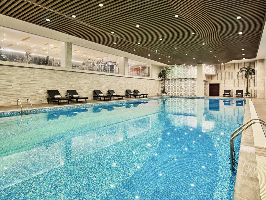 A large indoor swimming pool with lounge chairs and a tiled wall.