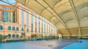 An indoor tennis court with a net, a tennis ball, and a Yonex-branded fence.