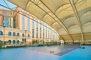 An indoor tennis court with a net, a tennis ball, and a Yonex-branded fence. - Hongshan Hotel (Wuhan)