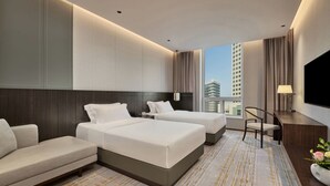 Ein Hotelzimmer mit zwei Betten, einer Sitzecke, einem Schreibtisch und einem Fernseher.